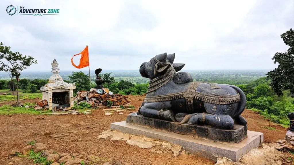 Black stone Nandi statue and Shiva Lingam with saffron flag on a scenic hilltop in Ananthagiri Hills Vikarabad